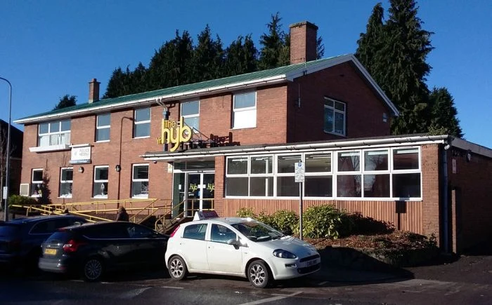 The red-brick exterior of Llanishen Hub with yellow hub signage above the entrance