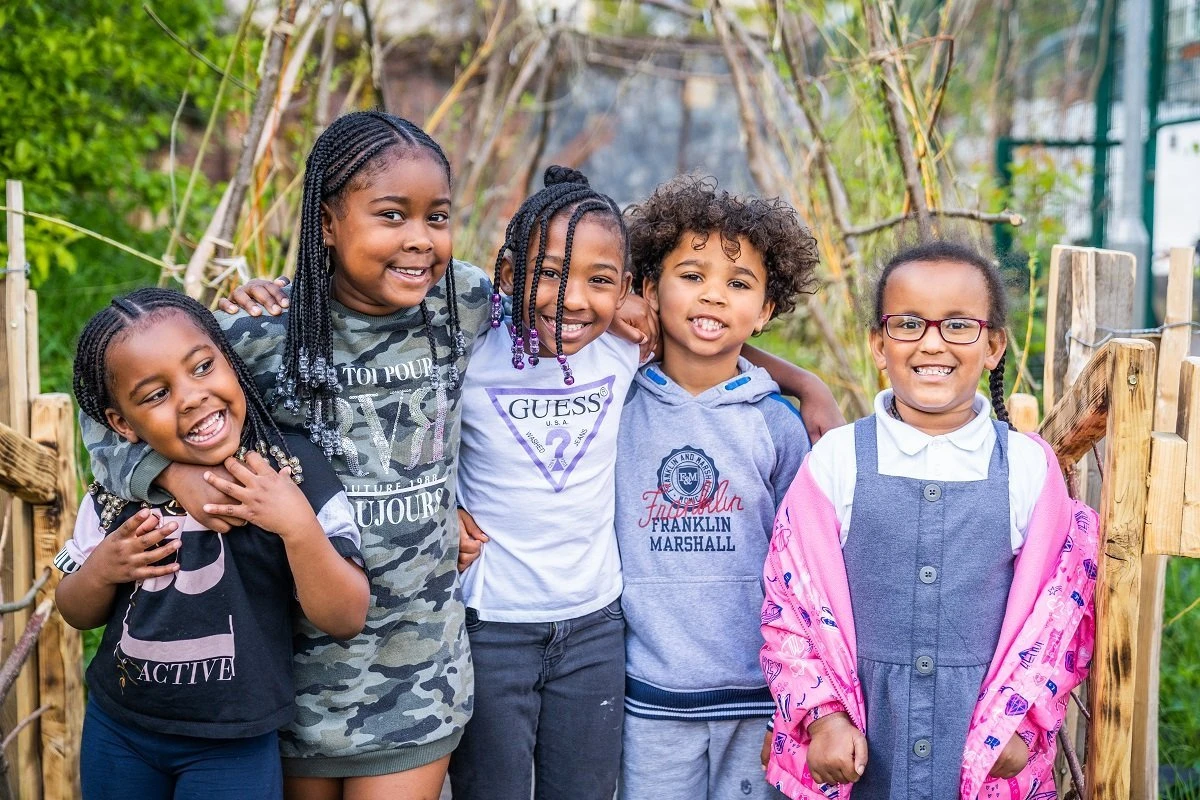 Children standing together beside wooden playground structures at Felix Road Adventure Playground