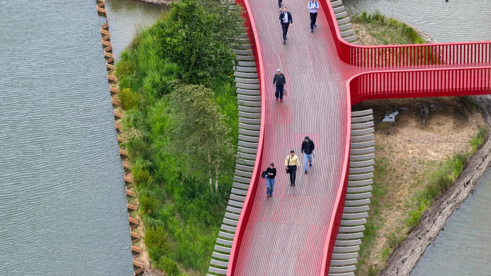People walking along Canada Dock’s curving red boardwalk between water and planted wetland islands