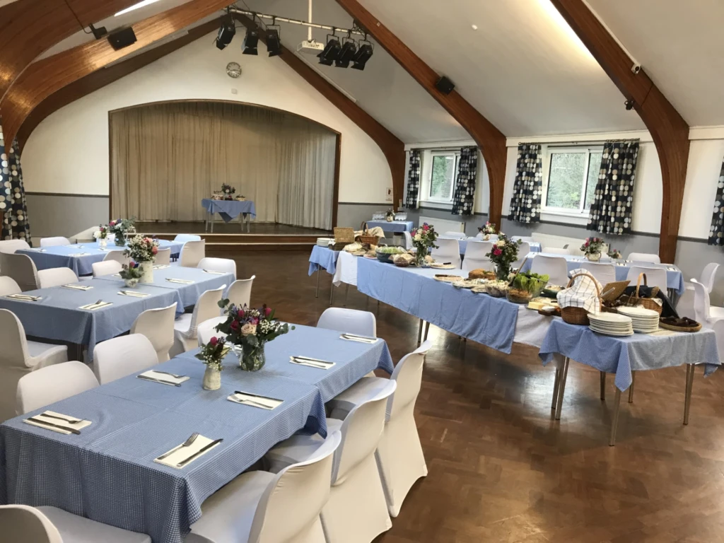 Blue-clothed tables, white-covered chairs and a buffet beneath wooden roof beams at Redcatch Community Centre