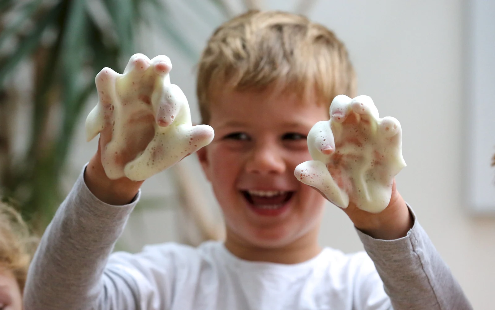 A child smiling with foamy hands in a Fun Science photograph