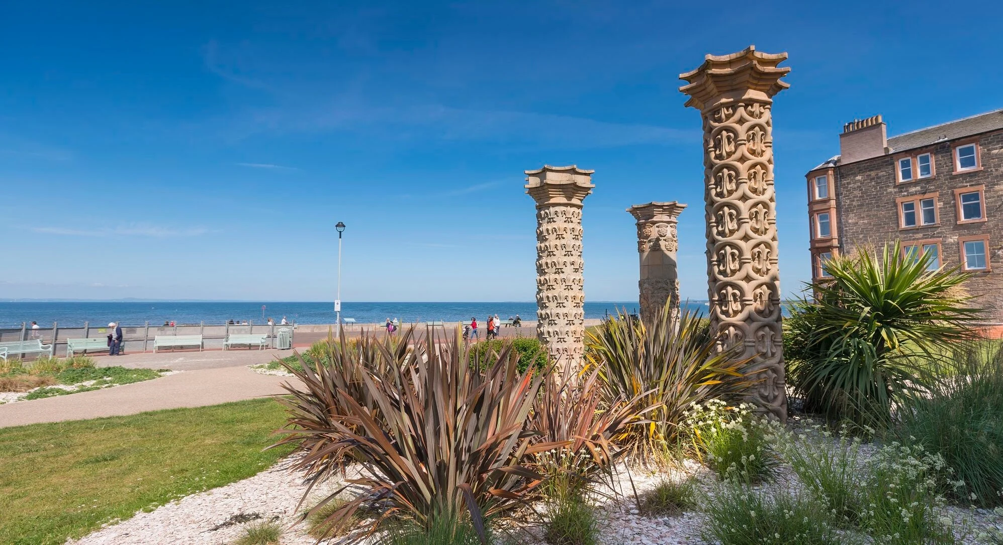 Carved stone columns and planting beside Portobello promenade, with the sea beyond