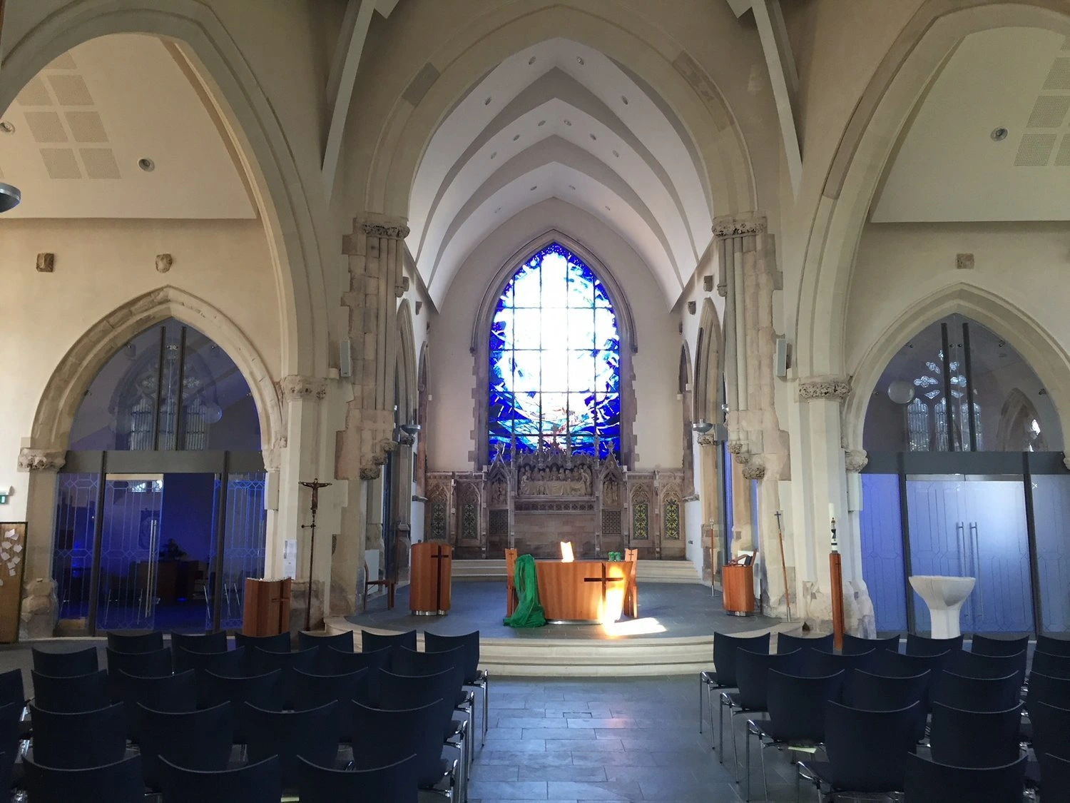 Arched interior and blue stained-glass window in St Barnabas Church, Erdington