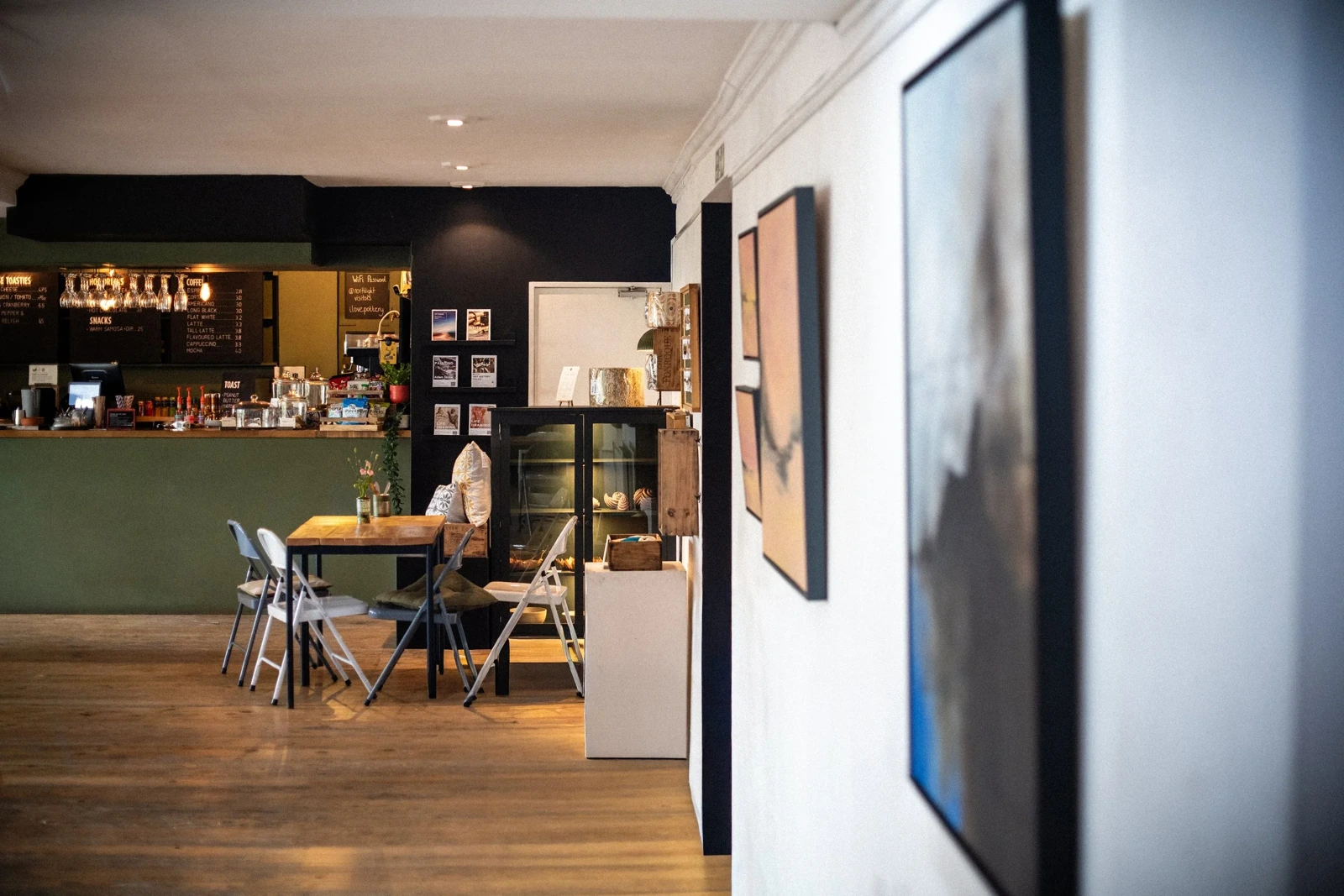 Tables and chairs beside the café counter and framed artwork at Northlight Arts Centre