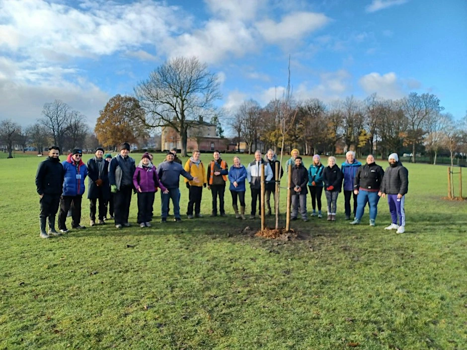 A group of community tree planters standing beside a newly planted tree in a park, in the council’s High Hazels Park event photograph