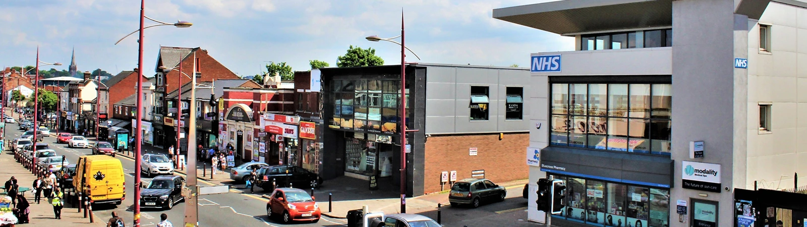 Shops, traffic and a modern NHS building along Soho Road in Handsworth
