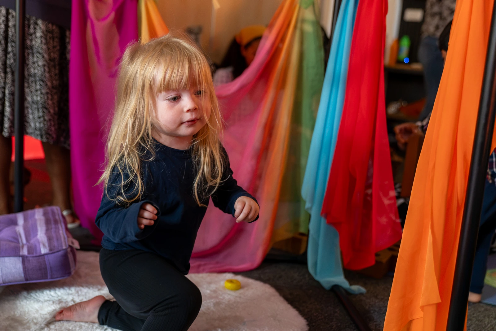 A child exploring colourful hanging fabrics at Dream Space playgroup at Hamara.
