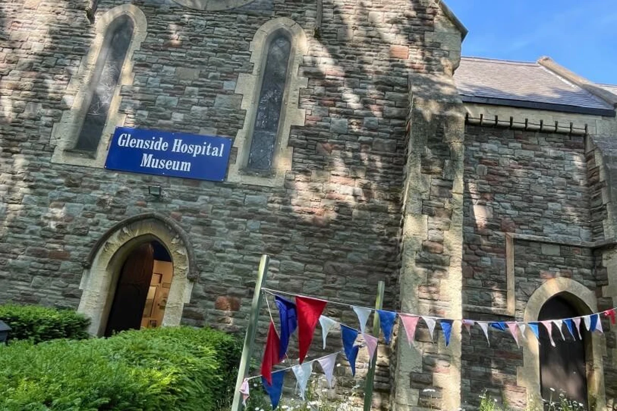 Stone facade and blue sign at Glenside Hospital Museum, with bunting outside the entrance