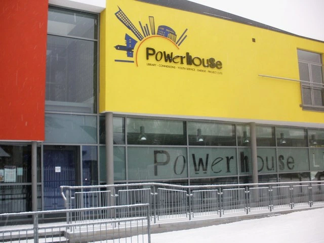 The yellow and red exterior of Moss Side Powerhouse, with its sign and ramp railings.