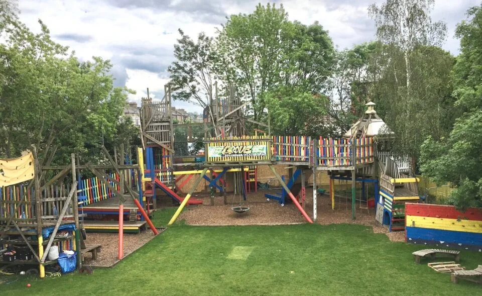Colourful timber climbing structures and grass at Grove Adventure Playground