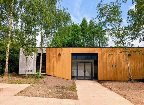 EcoPark’s timber-clad environmental centre behind a paved path, surrounded by trees