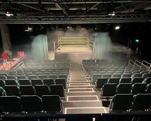 Rows of empty seats and a wrestling ring inside Belvoir Studio Theatre in an earlier pre-show setup