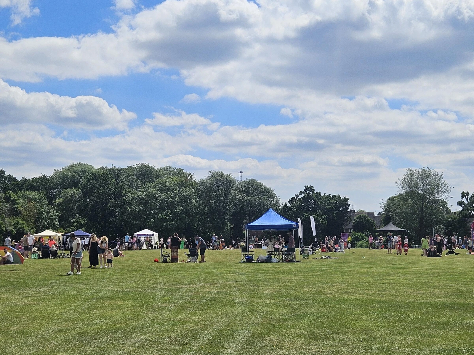People, gazebos and picnic chairs on the grass at Great Baddow Recreation Ground during a community gathering