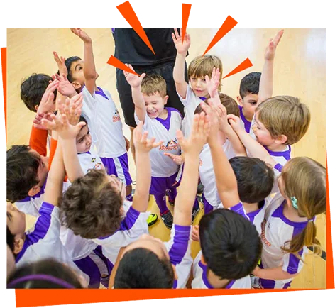 Children in SoccerDays kit raising their hands together indoors — organiser photograph