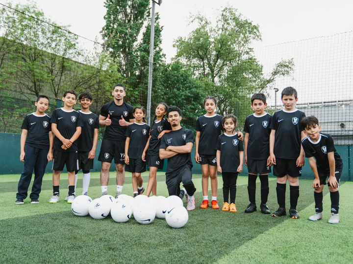 313 Football Academy players and coaches with footballs on an outdoor pitch — organiser photograph