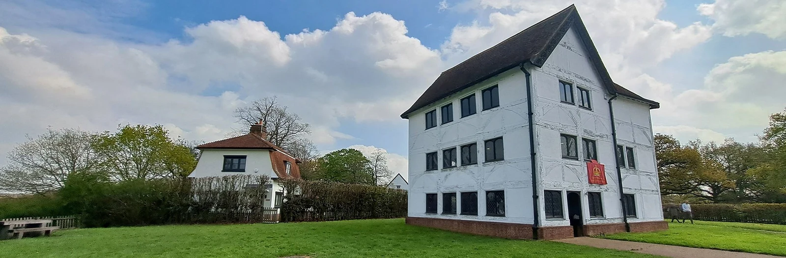 White timber-framed Queen Elizabeth’s Hunting Lodge beside a lawn