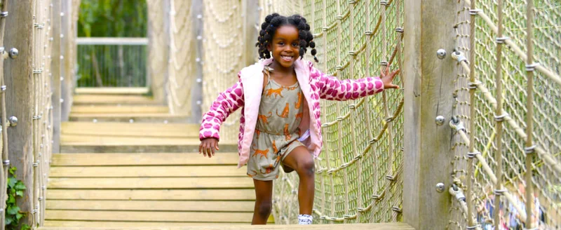 A child crossing the rope bridge at Tumbling Bay Playground