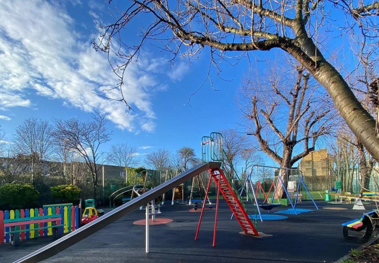 Slide, swings and colourful fenced play area at Papa’s Park