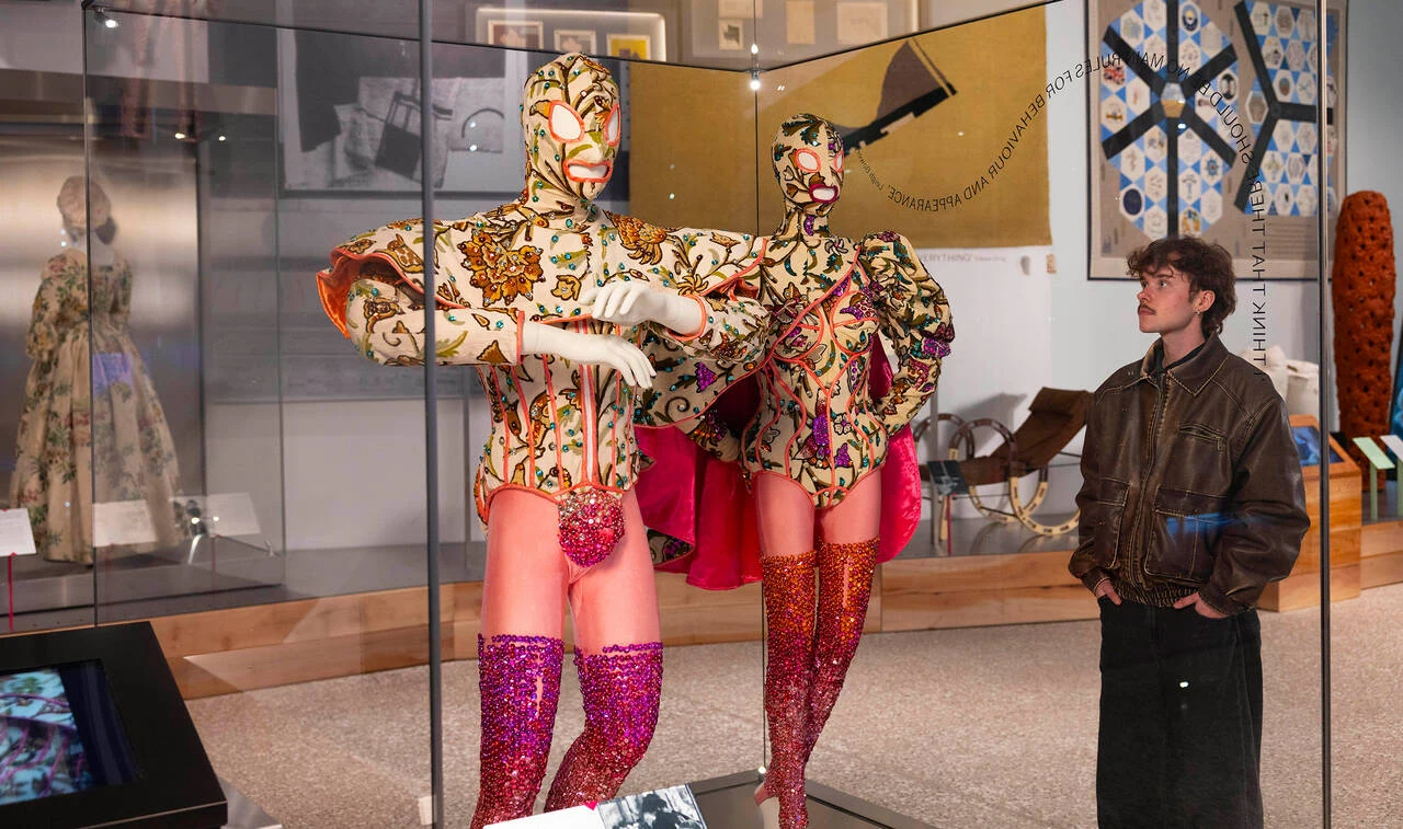 A visitor looking at colourful costumes in V&A East Museum’s Why We Make galleries