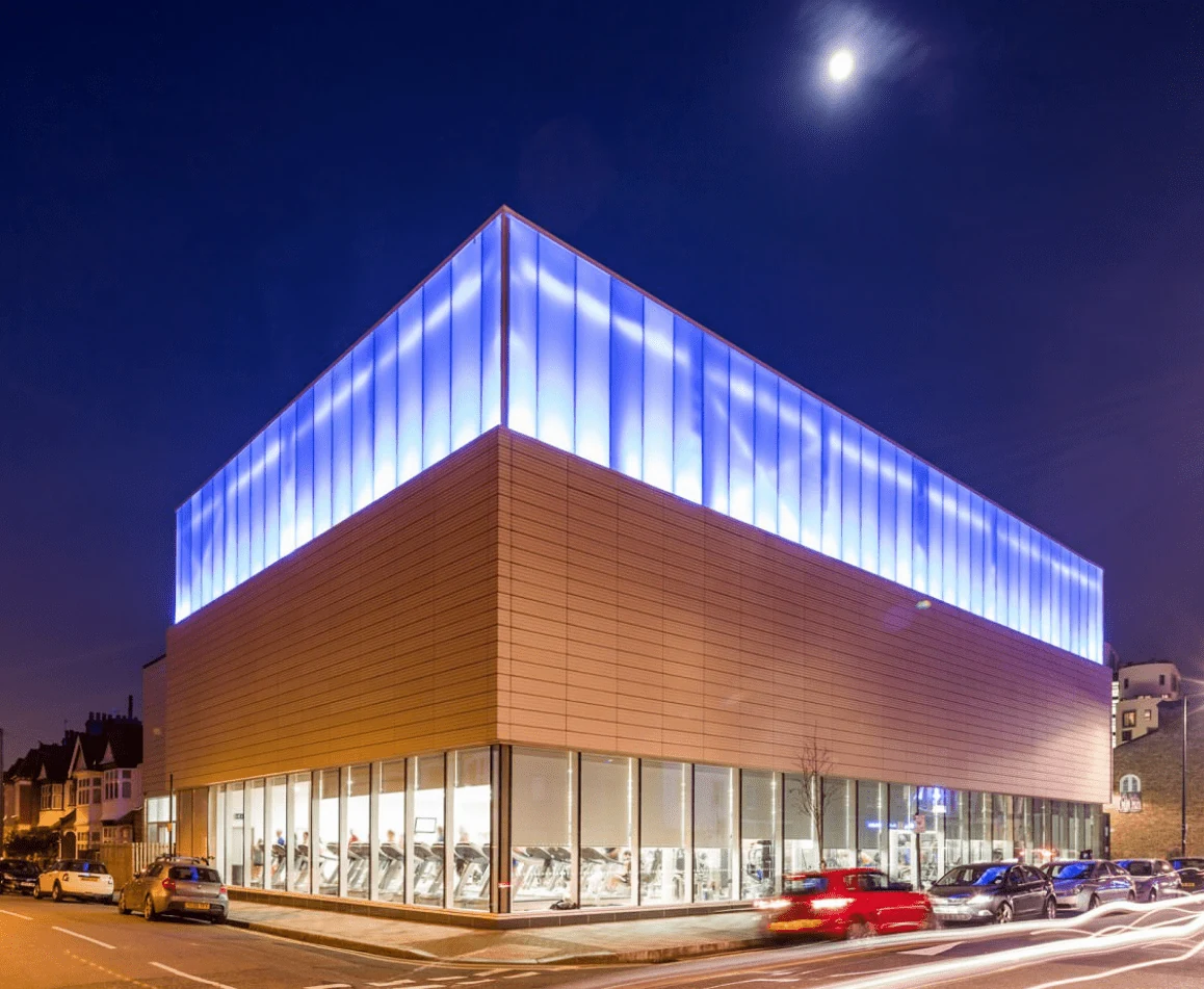 Clapham Leisure Centre exterior at night, with blue-lit upper panels and large ground-floor windows