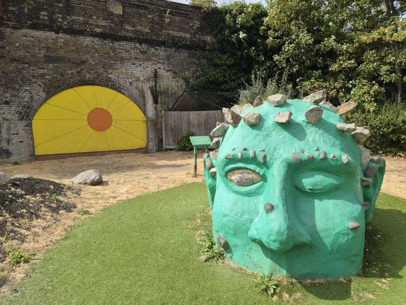 Green sculpted face and yellow arch at Acacia Road Playground